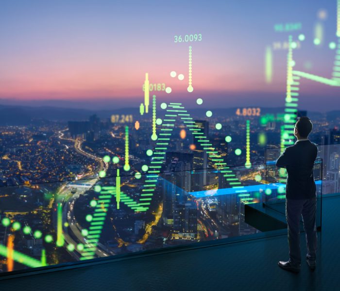 Businessman standing on open roof top balcony watching city night view with stock exchange market graph analysis background effect .  Concept of stock market  .